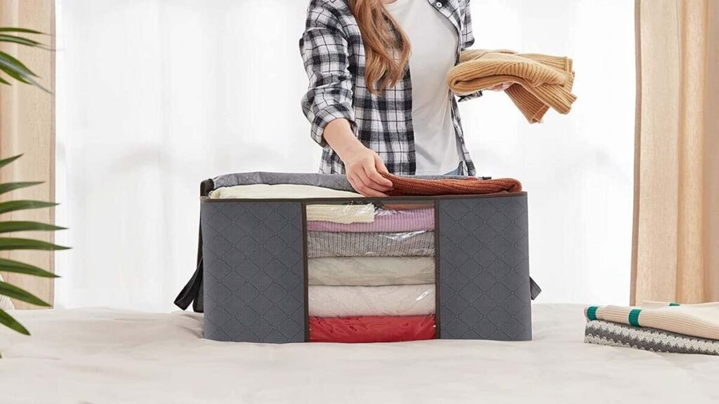 Three gray Lifewit 90L foldable clothes storage bags with zippered lids, reinforced handles and clear front window showing folded blankets